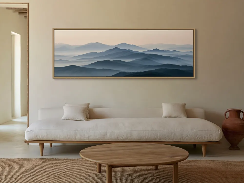 Panoramic mountain artwork in a natural frame above a linen daybed