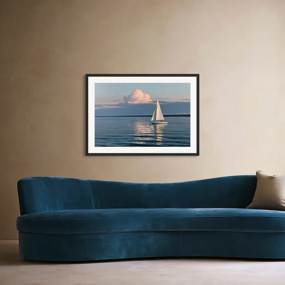 Sailboat at dusk print in a thin black frame with a white mat on a warm beige wall above a curved teal velvet sofa