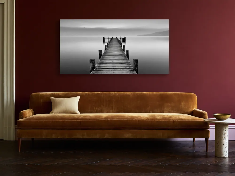 A black-and-white lake pier photograph as a stretched canvas in the Burgundy collector's sitting room