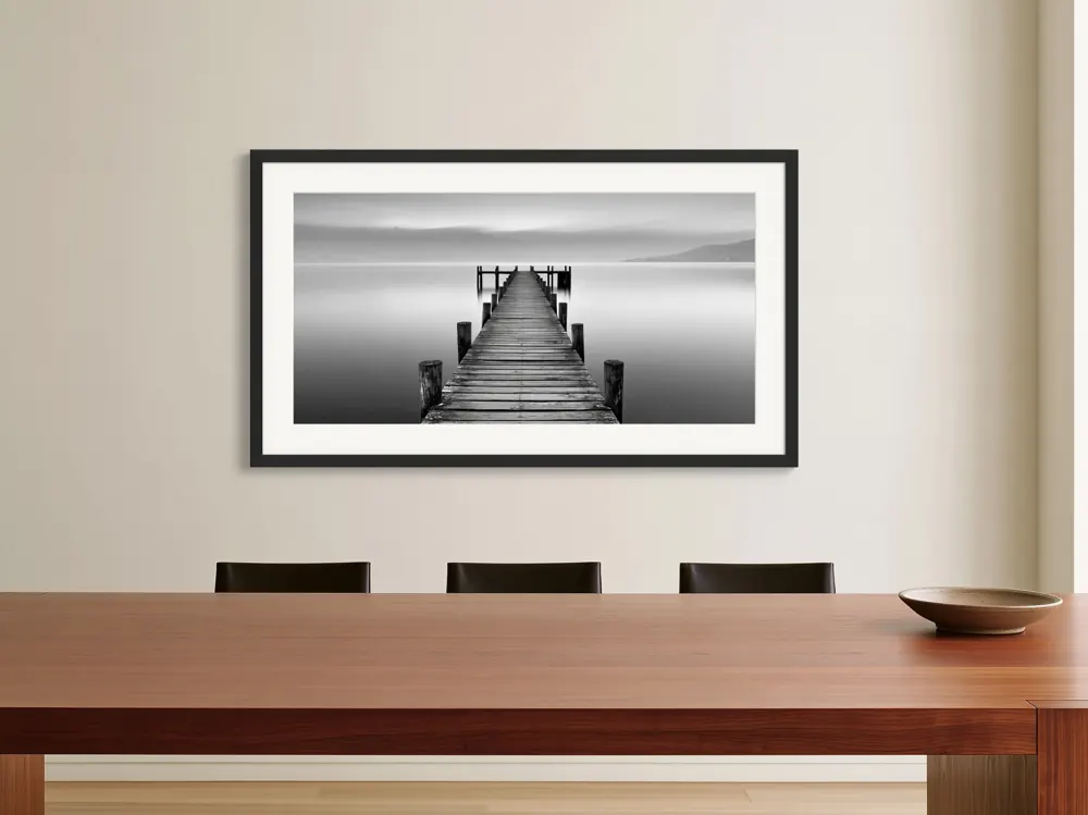 A black-and-white lake pier photograph as a black framed print with a white mat in the Cherrywood dining room