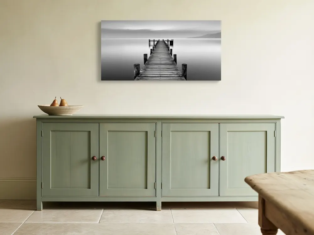 A black-and-white lake pier photograph as a stretched canvas in the Farmhouse dining, sage sideboard