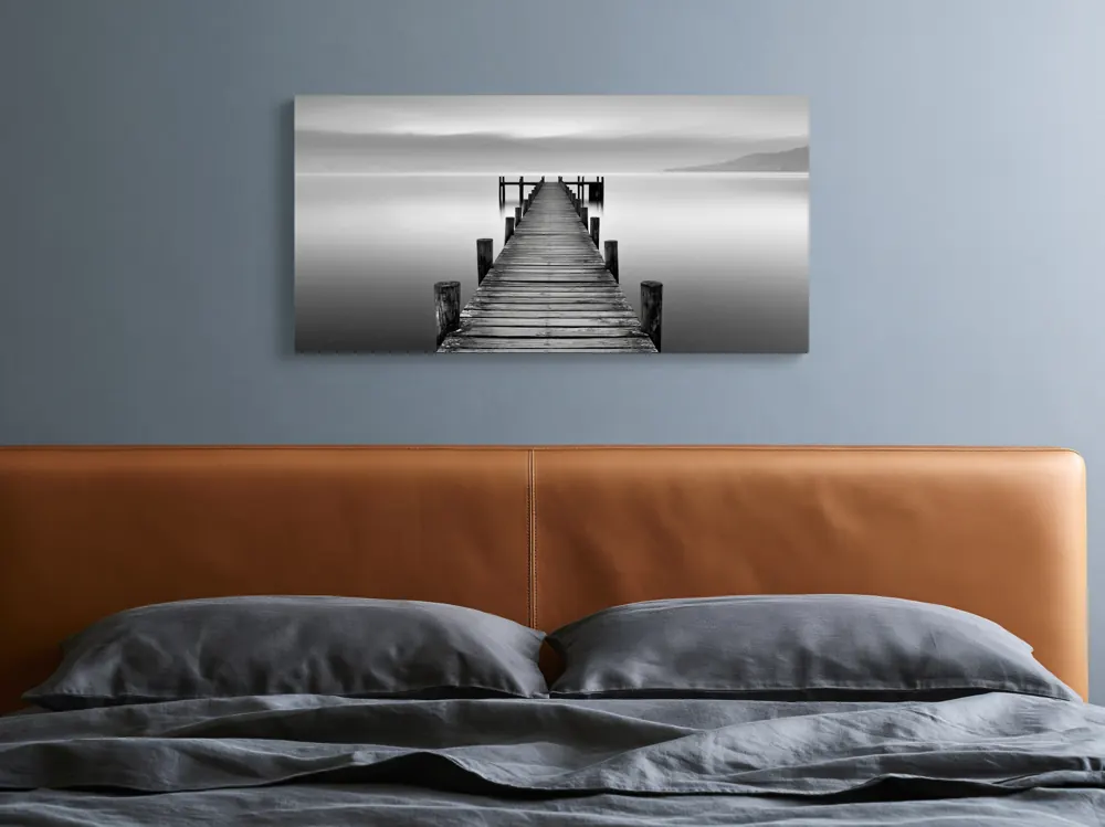 A black-and-white lake pier photograph as a stretched canvas in the Ink-blue bedroom
