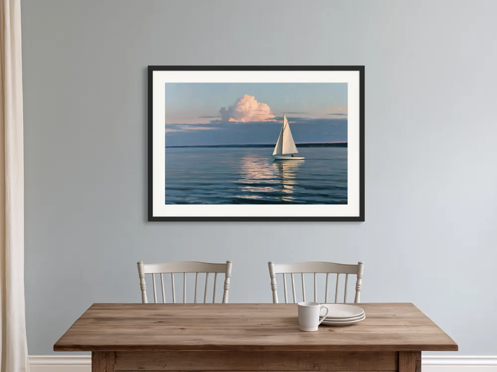 A sailboat-at-dusk oil painting as a black framed print with a white mat in the Lakehouse dining wall