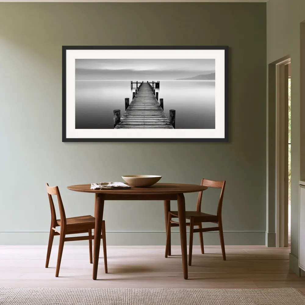 A black-and-white lake pier photograph as a black framed print with a white mat in the Sage dining room