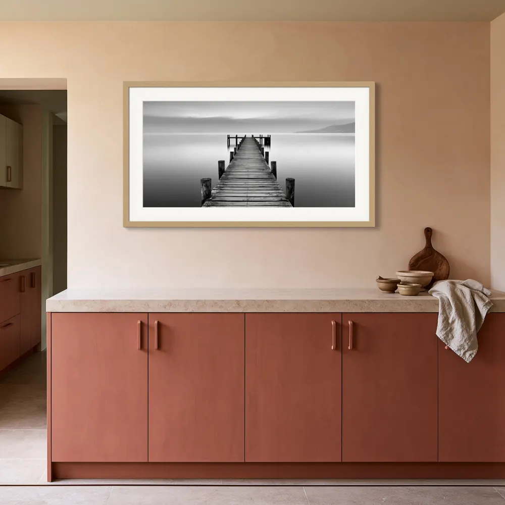 A black-and-white lake pier photograph as a natural oak framed print with a white mat in the Terracotta kitchen edge