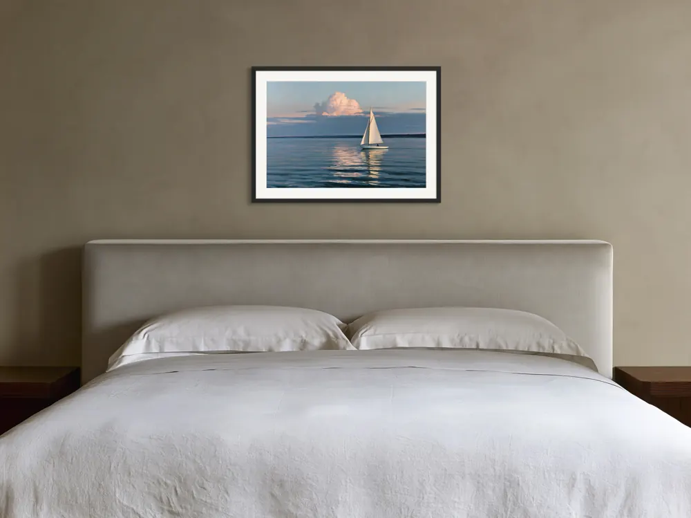 A sailboat-at-dusk oil painting as a black framed print with a white mat in the Tobacco upholstered bedroom